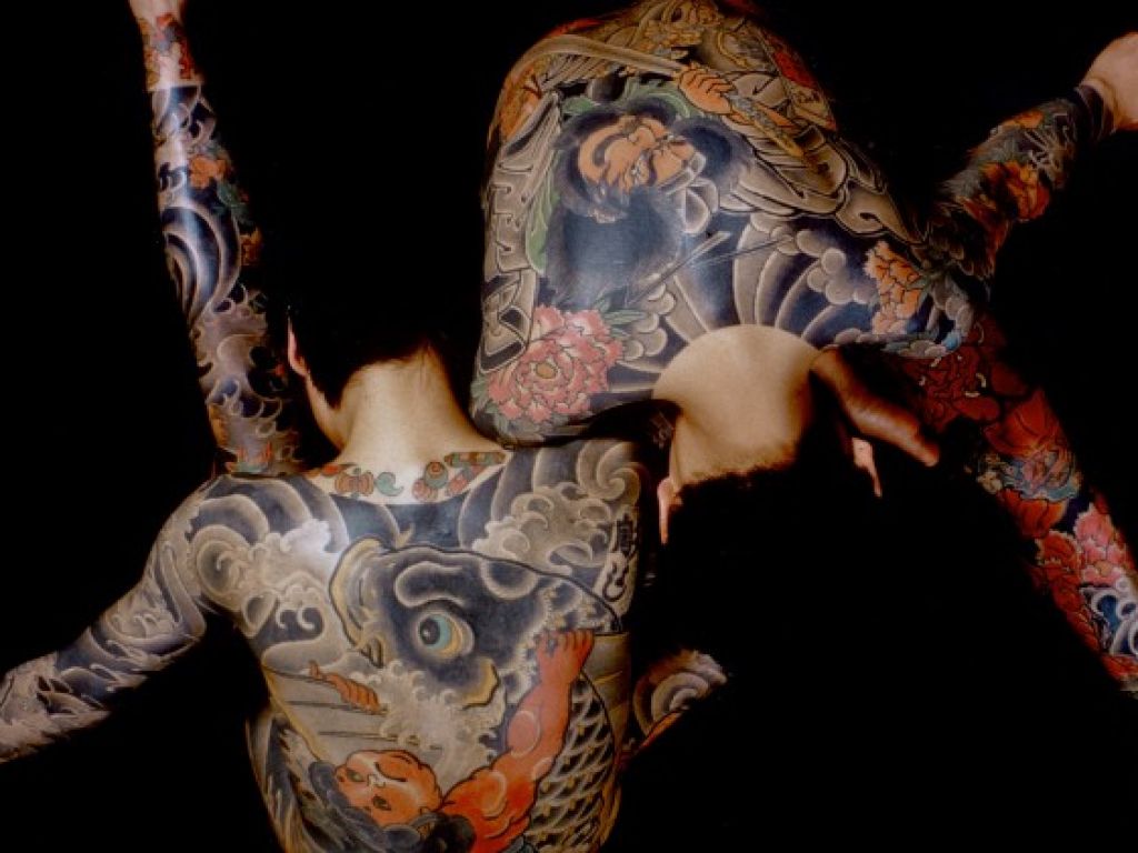 Dous homes ensinando as espaldas tatuadas.